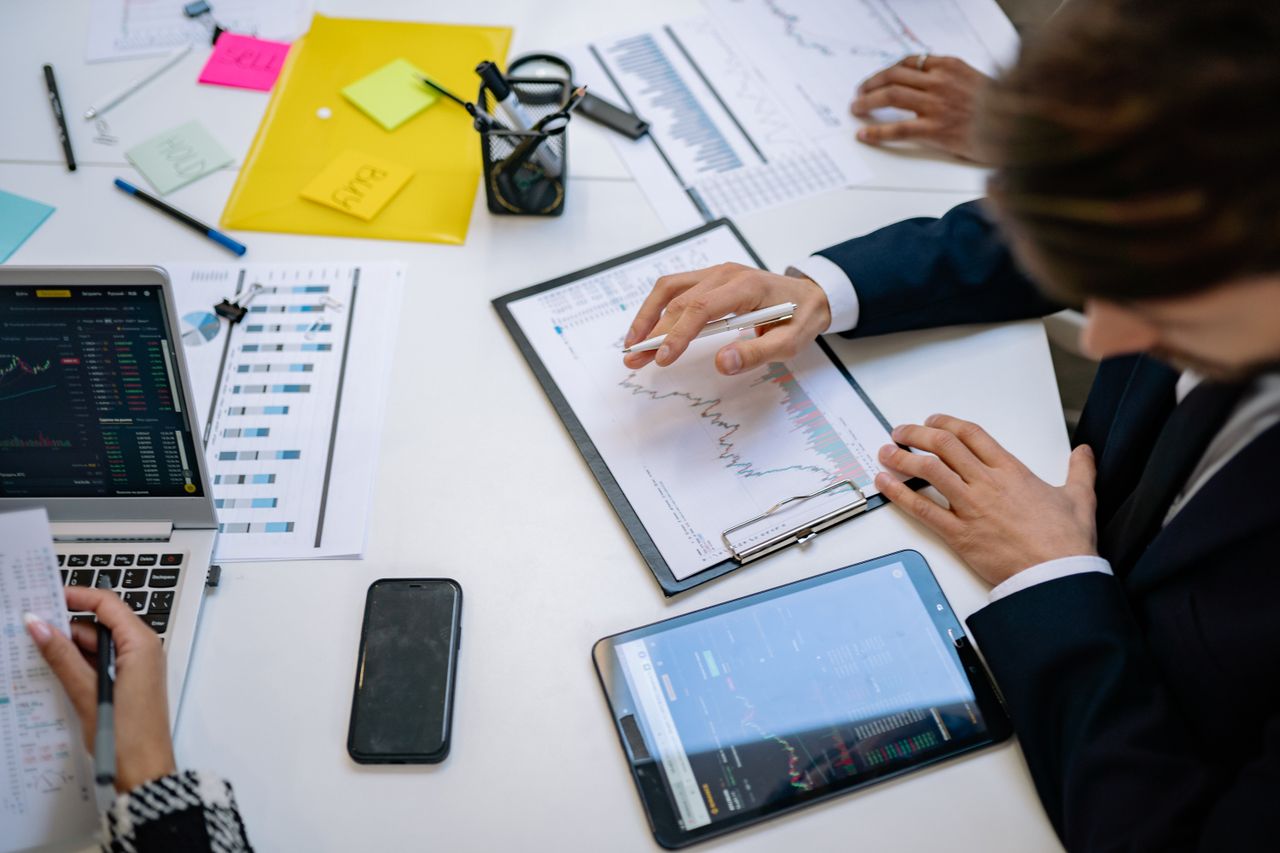 gallery-6 Team reviewing financial charts and digital data on tablets in an office setting.